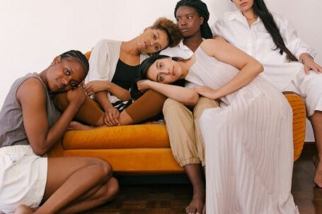 Diverse Beauty - Photo of Women Sitting on Orange Sofa