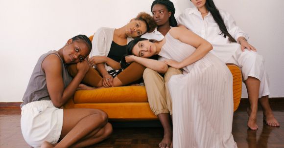 Diverse Beauty - Photo of Women Sitting on Orange Sofa