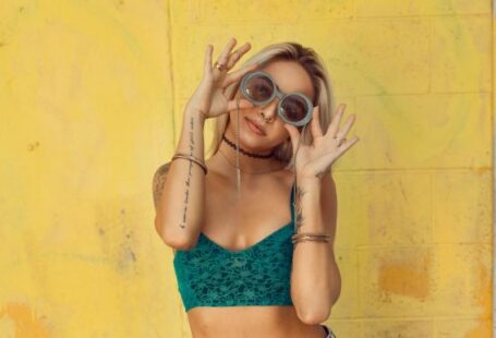 Fashion - woman in blue bralette holding sunglasses putting on her eyes