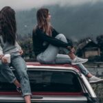 Fashion Journey - Two Women Sitting on Vehicle Roofs